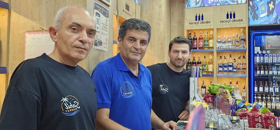 Sahil Market ekibi, logolu tişört ve polo yaka kıyafetleriyle dükkânda